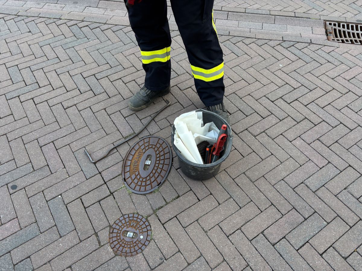Hydrant vor der Kontrolle mit Werkzeugeimer