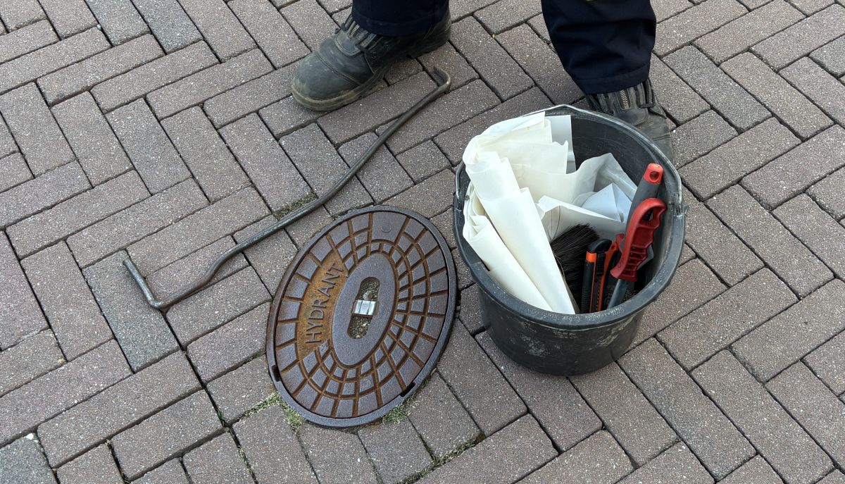 Hydrant vor der Kontrolle mit Werkzeugeimer