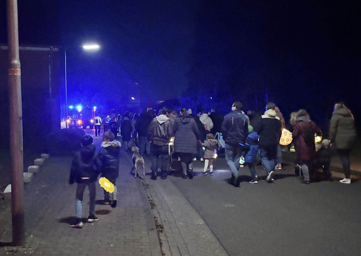 Kinder mit Laternen und LF20 mit Blaulicht im Hintergrund. Das Bild ist bei Nacht.