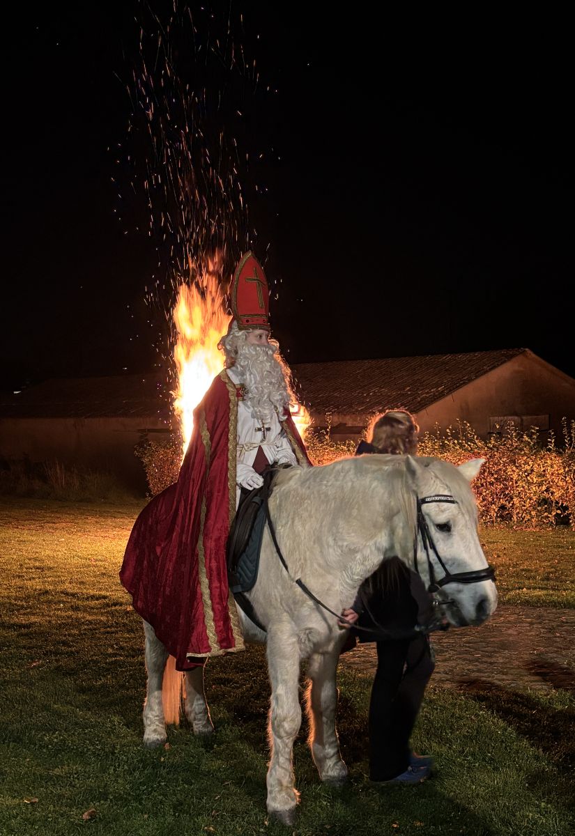 St Martin auf dem Pferd in Nahaufnahme und von seitlich vorne. Im Hintergrund das Feuer im Vollbrand.