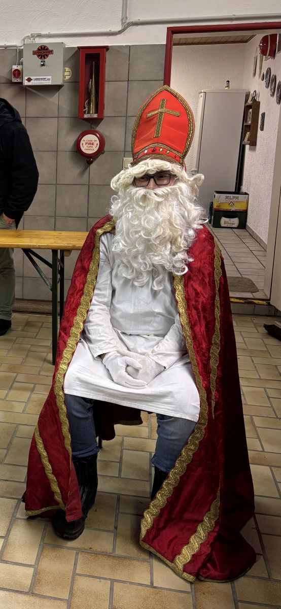 St Martin auf einem Stuhl, wartend auf die Leckertütenübergabe an die Kinder.