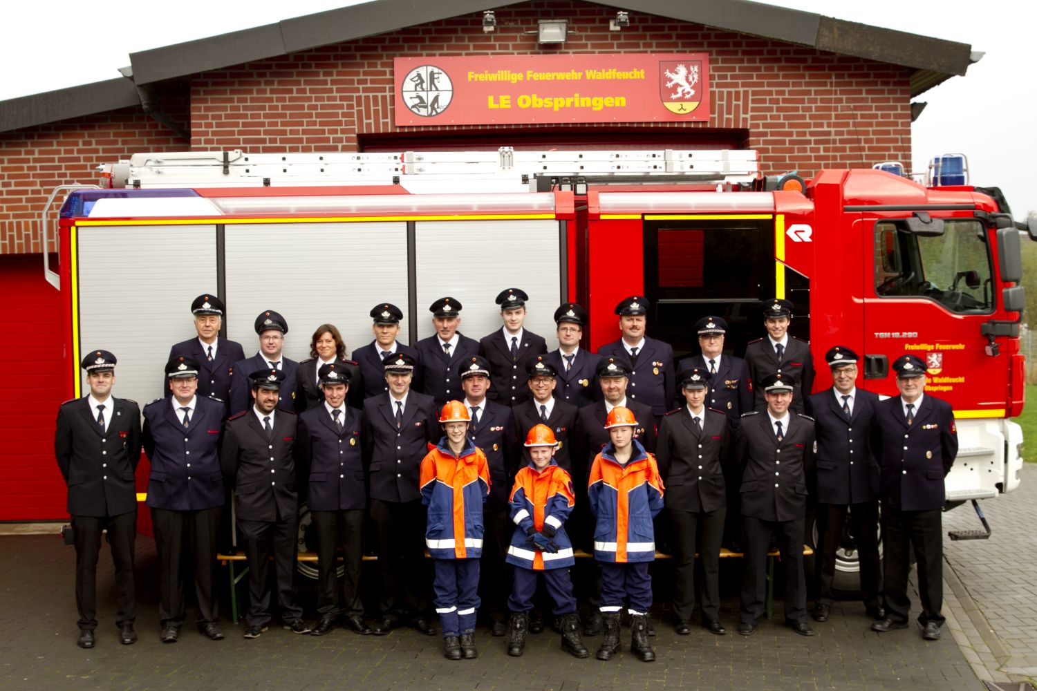 Gruppenbild der Feuerwehr vor dem Gerätehaus und dem LF20