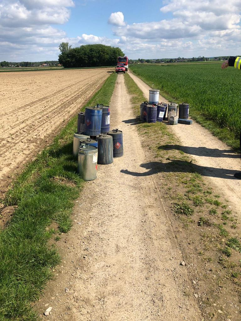 Ölfässer auf einem Feldweg. Feuerwehrautos im Hintergrund.
