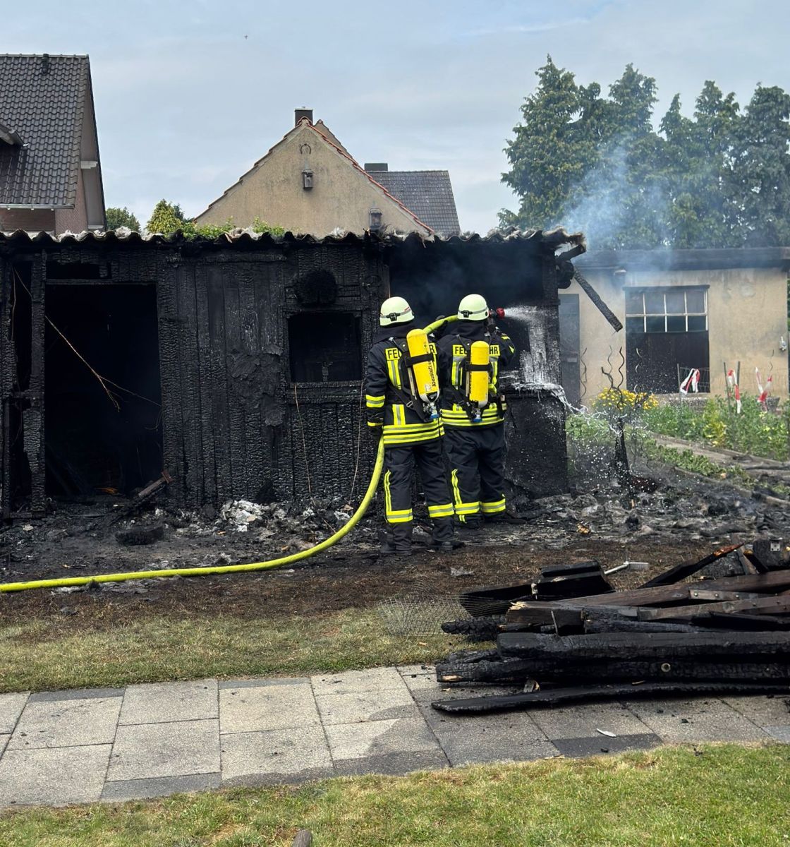 zwei Feuerwehrleute beim Löschen der Gartenlaube