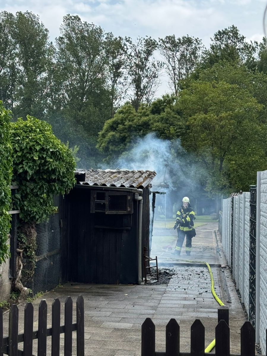 Feuerwehrmann neben der abgebrannten Gartenlaube