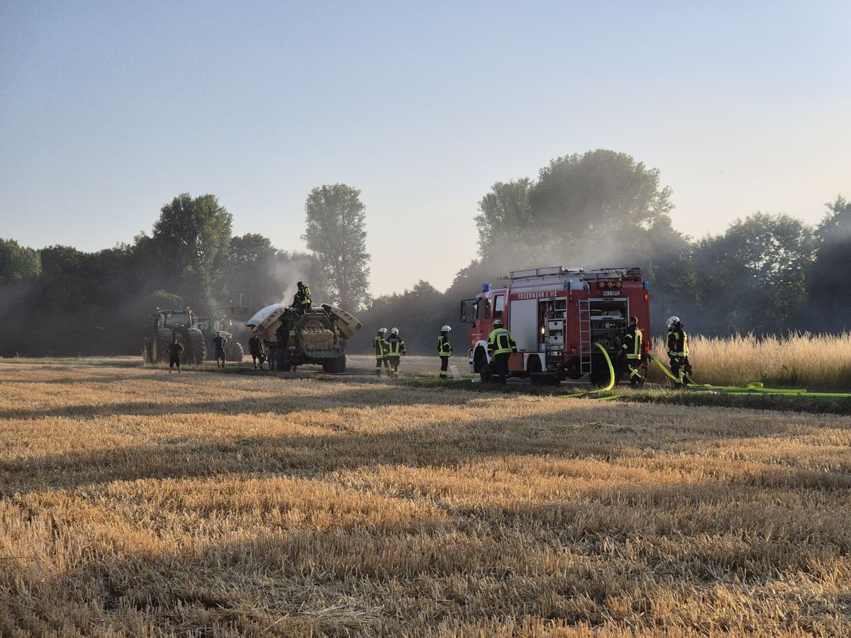 qualmende Landwirtschaftsmaschine mit Feuerwehrleuten und Feuerwehrauto - Bild aus der Nähe