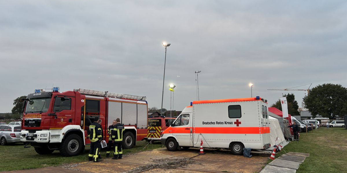 geparkter LF neben einem RTW mit Feuerwehrleuten bei der Lagebesprechung.